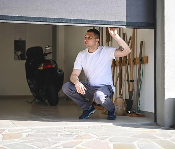 Technician inspecting and repairing a residential garage door inside a garage.