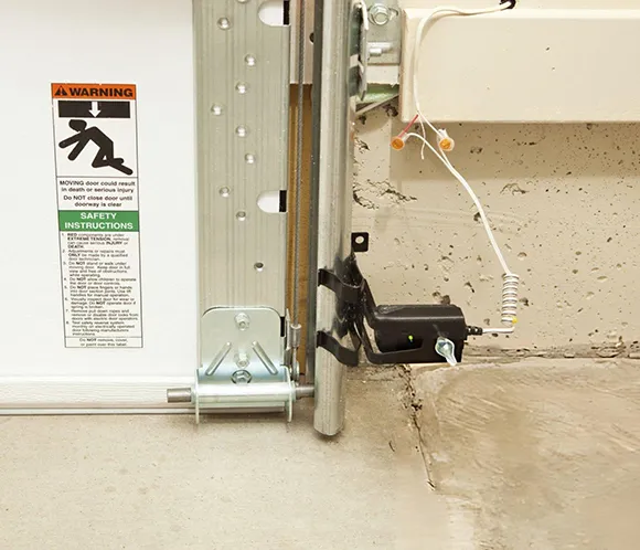 Detailed view of a garage door safety sensor device mounted on a garage door frame.