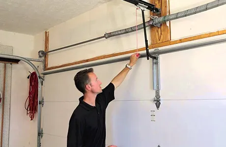 Technician repairing garage door spring mechanism inside residential garage