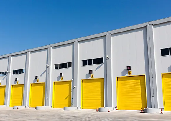White commercial building with multiple yellow overhead roll-up doors at loading dock in Frisco, TX