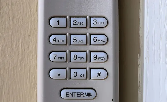 Close-up of a digital garage door keypad mounted on a wall with numbered buttons and enter key in Rowlett, TX.
