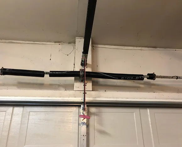Close-up of balanced torsion and extension springs mounted on garage door overhead track.