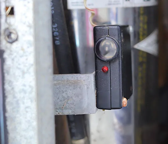 Close-up view of safety beam sensor device installed on the side of a garage door frame.
