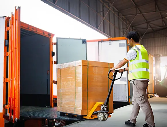Worker manually unloading a pallet jack at a loading dock facility with hydraulic dock lifts installed in Flower Mound, TX.