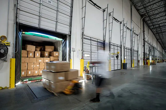 Warehouse interior with industrial loading dock equipment including pallets and boxes being moved in Plano, TX