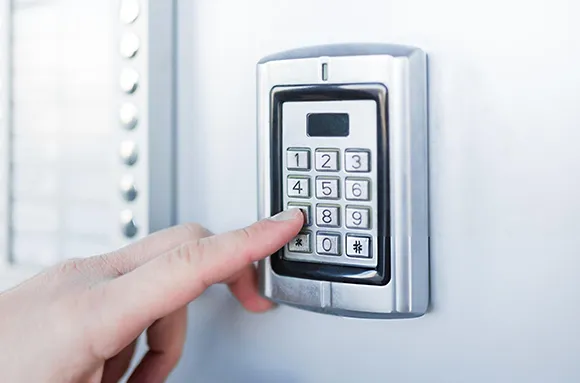Close-up of hand using a keyless garage entry keypad installed on exterior wall in Frisco, TX.