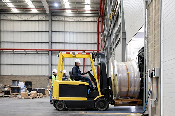 Forklift operator using a yellow forklift to handle materials inside a warehouse for loading dock levelers installation in Houston, TX.