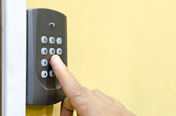 Side view of a finger pressing numbers on a smart garage door keypad in Flower Mound, TX.