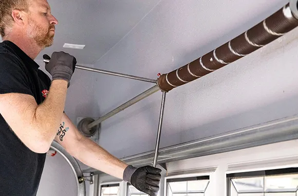 Technician repairing torsion garage door spring inside residential garage in Rowlett, TX