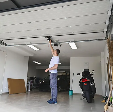 Professional technician performing maintenance on a garage door spring in a residential garage.